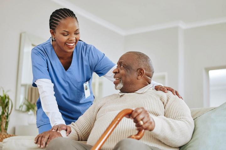 A caregiver walking beside an older man using a cane